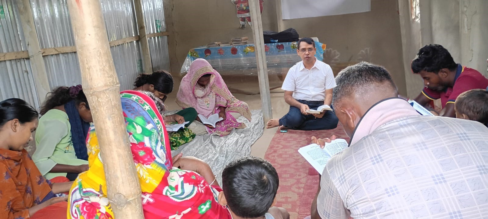 Bangla-language Bible study gathering with participants reading Scripture together